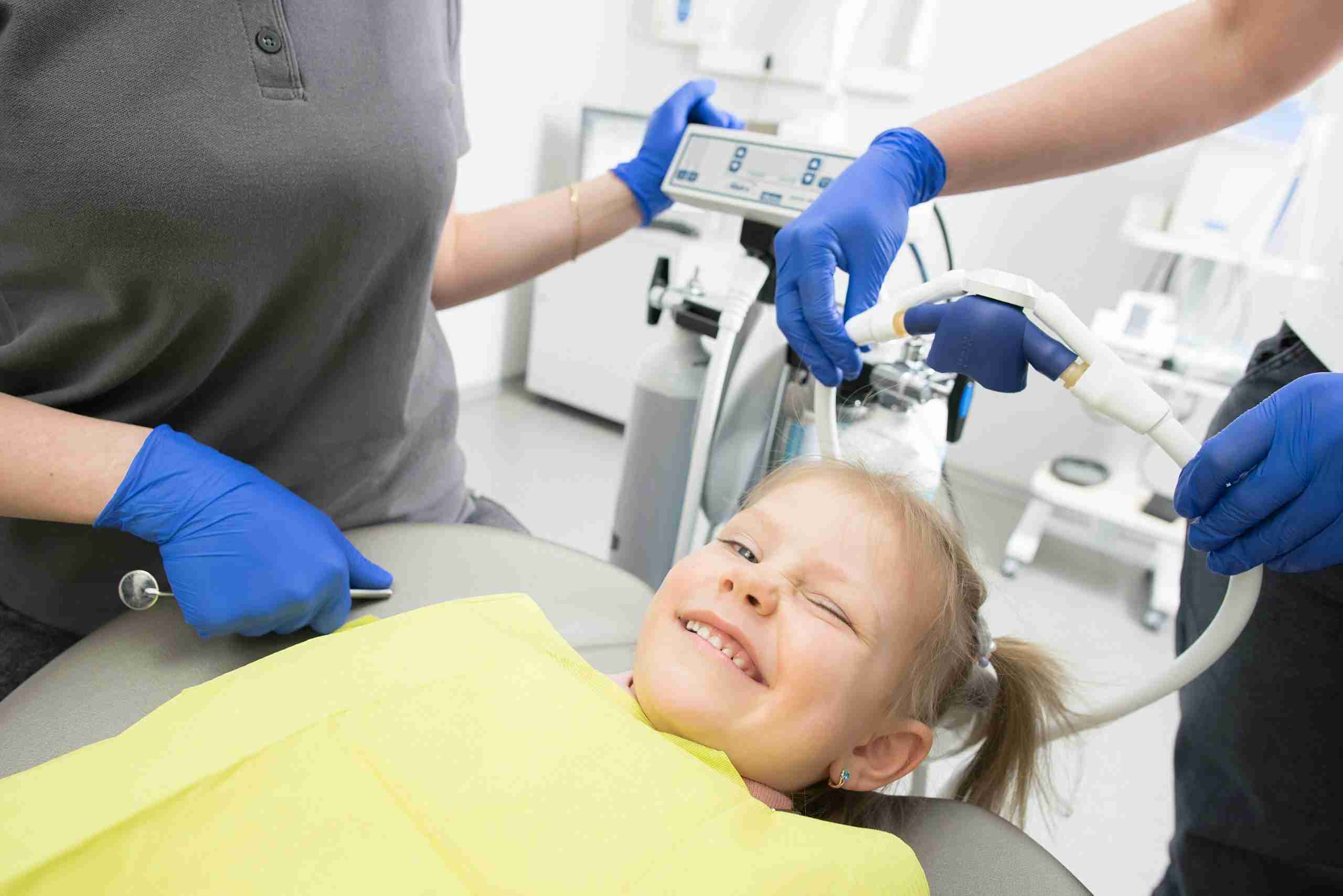 Detailed shot of a dentist applying veneer to a woman's teeth during a dental procedure.