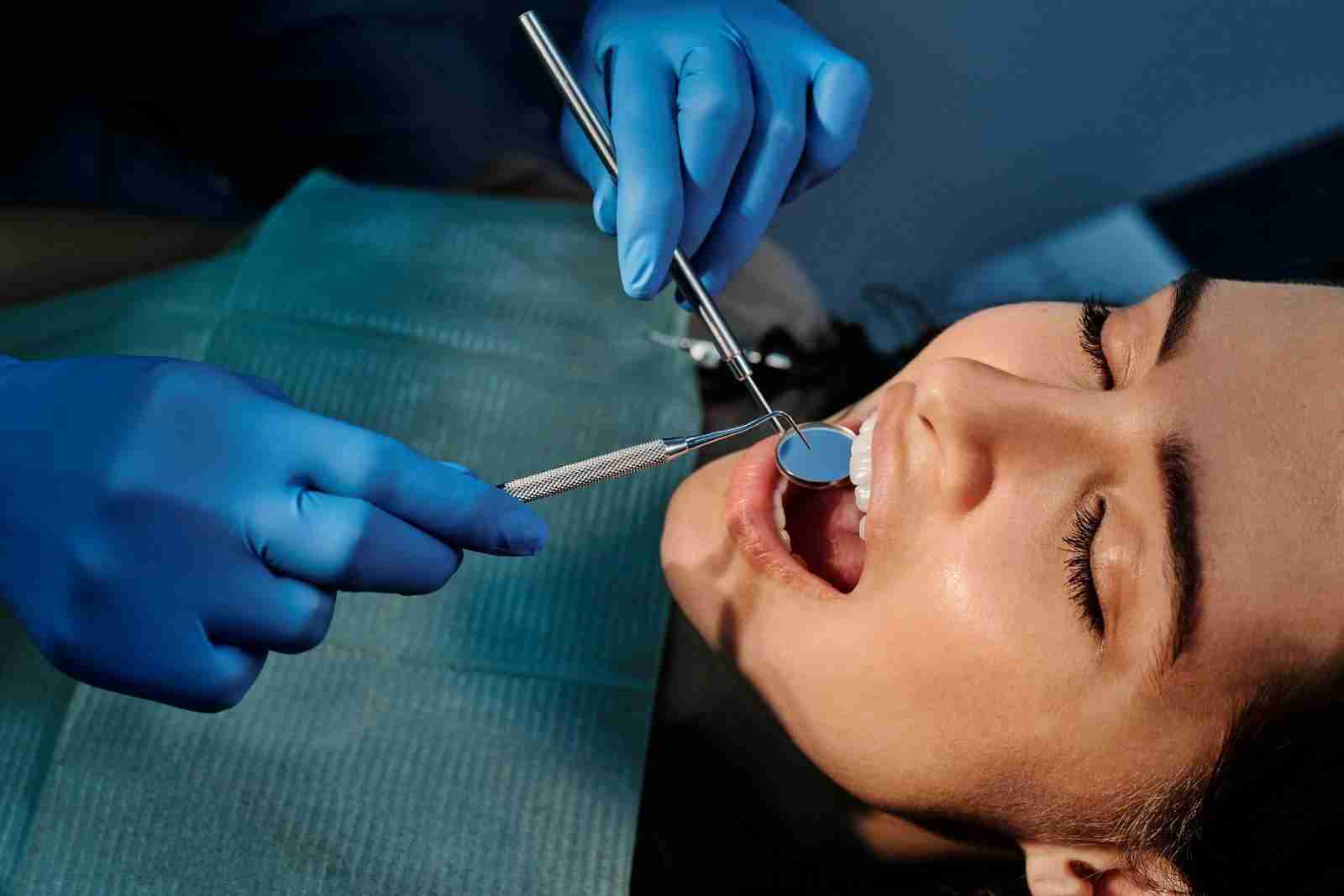 Detailed shot of a dentist applying veneer to a woman's teeth during a dental procedure.