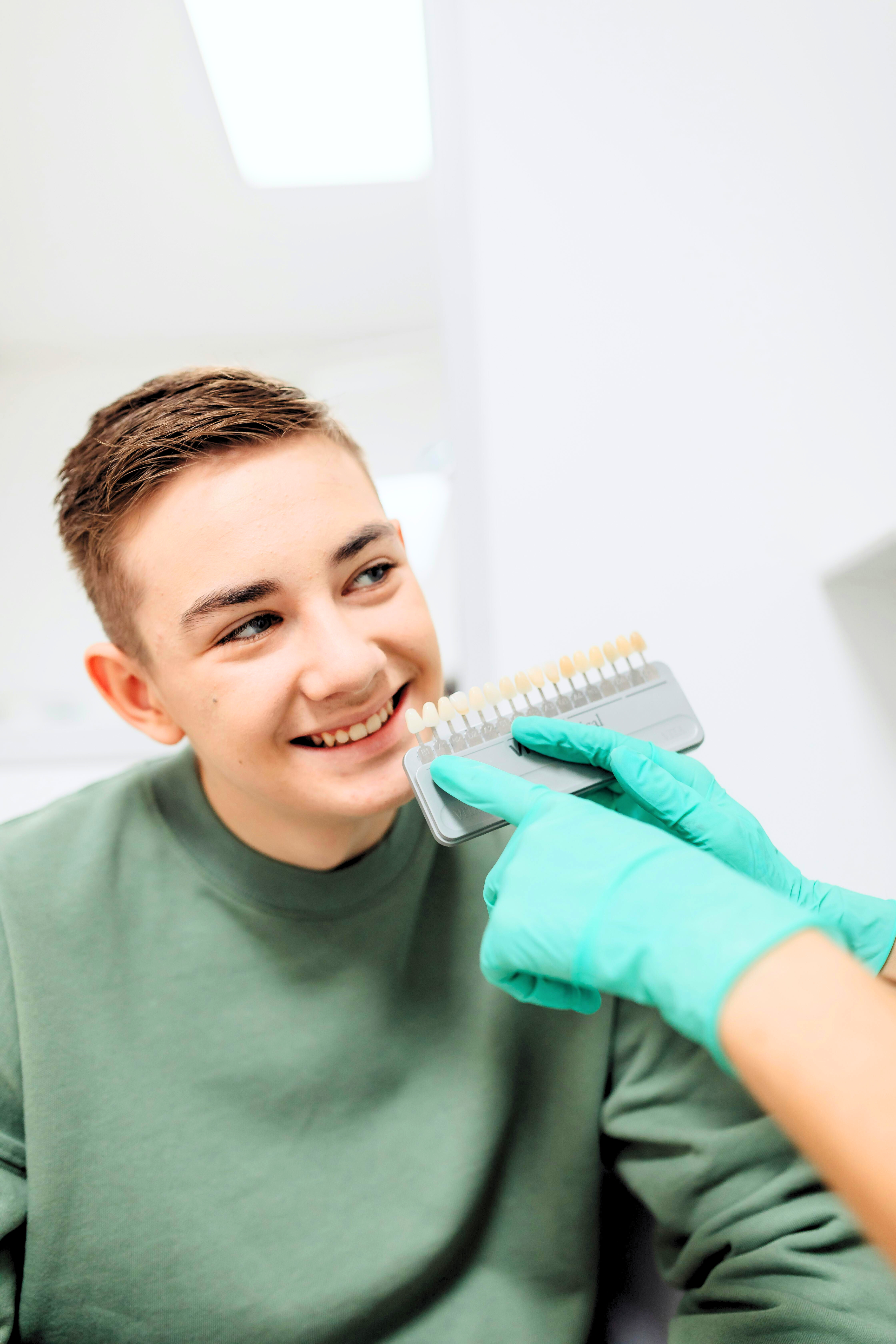 Detailed shot of a dentist applying veneer to a woman's teeth during a dental procedure.