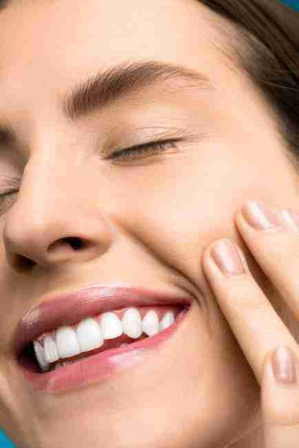 Detailed shot of a dentist applying veneer to a woman's teeth during a dental procedure.